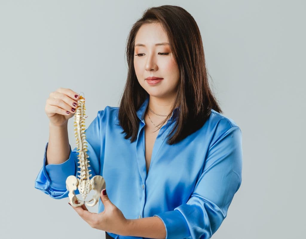 Daniela Kitamura segurando um modelo anatômico da coluna vertebral